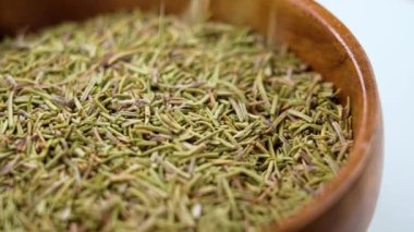 Ahşap kasede kurutulmuş biberiye baharatı. Ağır çekimde düşen kurumuş kokulu bitkiler. Makro atış. Döndürme