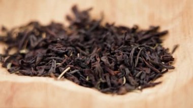 Kurutulmuş siyah çay yaprakları, kekik otuyla birlikte kırsal ahşap kasede. Kuru, sağlıklı bitkisel şifa maddesi. Döndürme