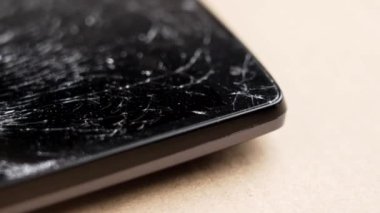 Kahverengi bir yüzeyde cep telefonunun siyah dokunmatik ekranı kırılmış. Makro. Döndürme