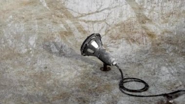 Waterproof electric lamp in an empty dirty city fountain with reflection in the water. Maintenance of pool lighting equipment concept