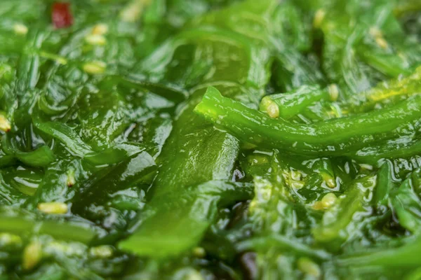Delicious marinated green wakame seaweed salad with sesame seeds close up