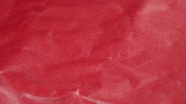 Crumpled red gift wrapping paper texture close up. Abstract background. Rotation