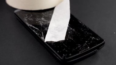 Broken smartphone with crushed touch screen display repaired with adhesive paper tape. Service maintenance and insurance of electronic device concept