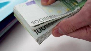 Cash one hundred Euro banknotes in the hands of a businessman closeup