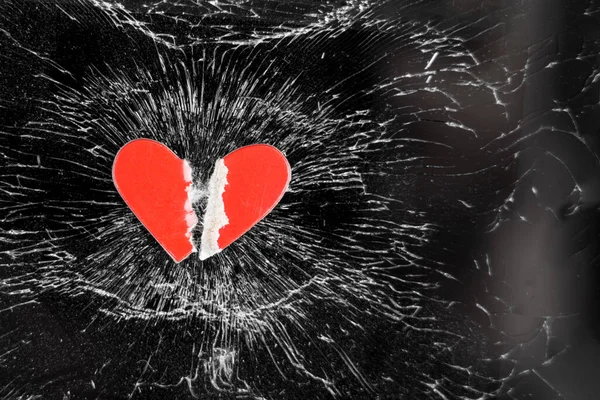 Ripped red paper heart on the crushed glass of a black smartphone. Love romantic relationship break up concept. Copy space