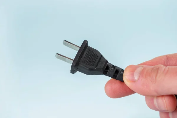 US power plug with cable on a blue background in hand closeup