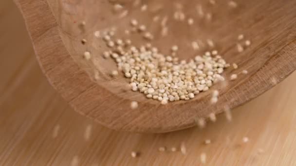 木製のボウルに落ちる調理されていないキノアの穀物は スローモーションで閉じます グルテンフリー種子 — ストック動画