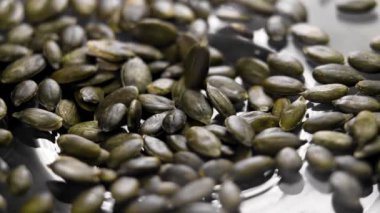 Çiğ kabak çekirdekleri cam bir yüzeye düşüyor. Keto diyet yemeği. Döndürme. Yavaş çekim
