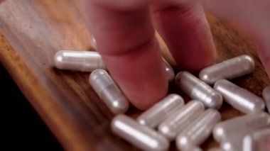 Ahşap bir kapta vitamin doğal ilaç kapsülleri var. El hapları ağır çekimde alıyor.