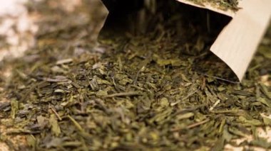 Kurutulmuş yeşil sencha çay yapraklarını kâğıt poşetlerle kaplamak. Döndürme. Sağlıklı doğal içecek. Yavaş çekim