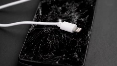 Kırık camlı dokunmatik beyaz kablolu siyah akıllı telefon ekranı. İletişim sorunları kavramı