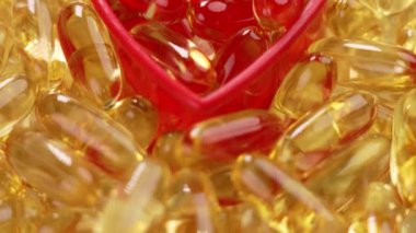 Altın Omega 3 kapsülleri kırmızı kalp şeklinde. Doğal deniz balığı takviyeleri. Kapat.