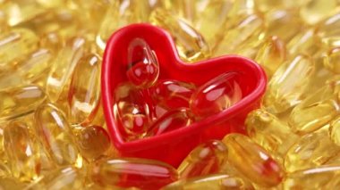 Altın Omega 3 takviyesi, deniz balığı yağı. Kırmızı kalp şeklinde doğal sarı kapsüller. Kapat.