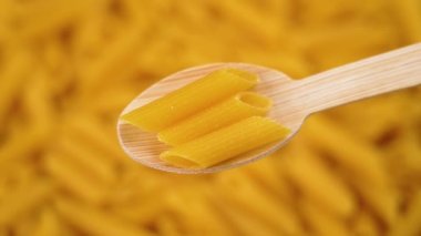 Diyet mercimek glütensiz makarna, arka planda dönen yavaş çekimde ahşap bambu kaşığa düşüyor. Beslenme makarnası.