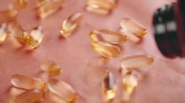 Portakal omega 3 somon balığı yağı kapsülleri eczane şişesinden yavaş çekimde dağılıyor. DHA ve EPA sağlıklı denge ile doğal gıda takviyesi