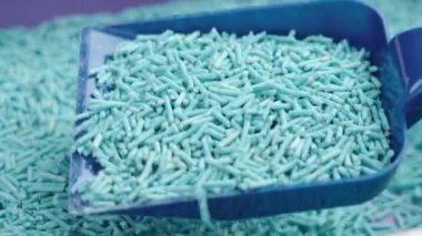 Plastik kepçe içinde mavi soya çürütülebilir dolgusu olan temiz kedi kumu kutusu.