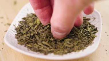 El, sencha yeşil çayını alır kuru yaprakları yakın. Ağır çekim. Geleneksel Japon içeceği.