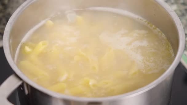 健康的なグルテンフリーペンネパスタ沸騰したお湯の鍋にストーブの上で料理 — ストック動画