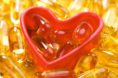 Plastik bir kalp şeklindeki Omega 3 kapsülü takviyesi