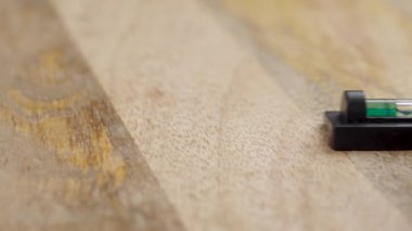 Mühendis eli, küçük alet ruh seviyesini yeşil sıvı ve baloncukla ahşap yüzeye koyar