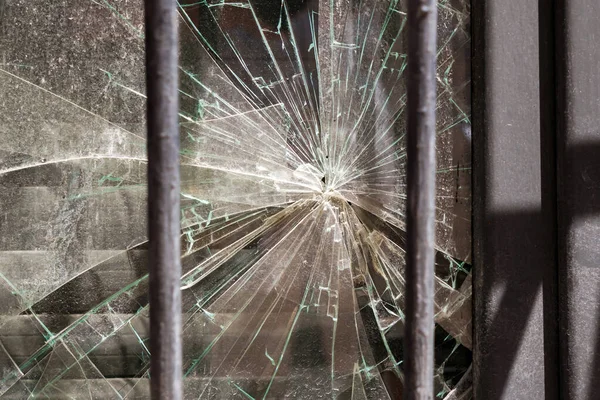 Broken shattered glass behind the window bars. Criminal hacking concept