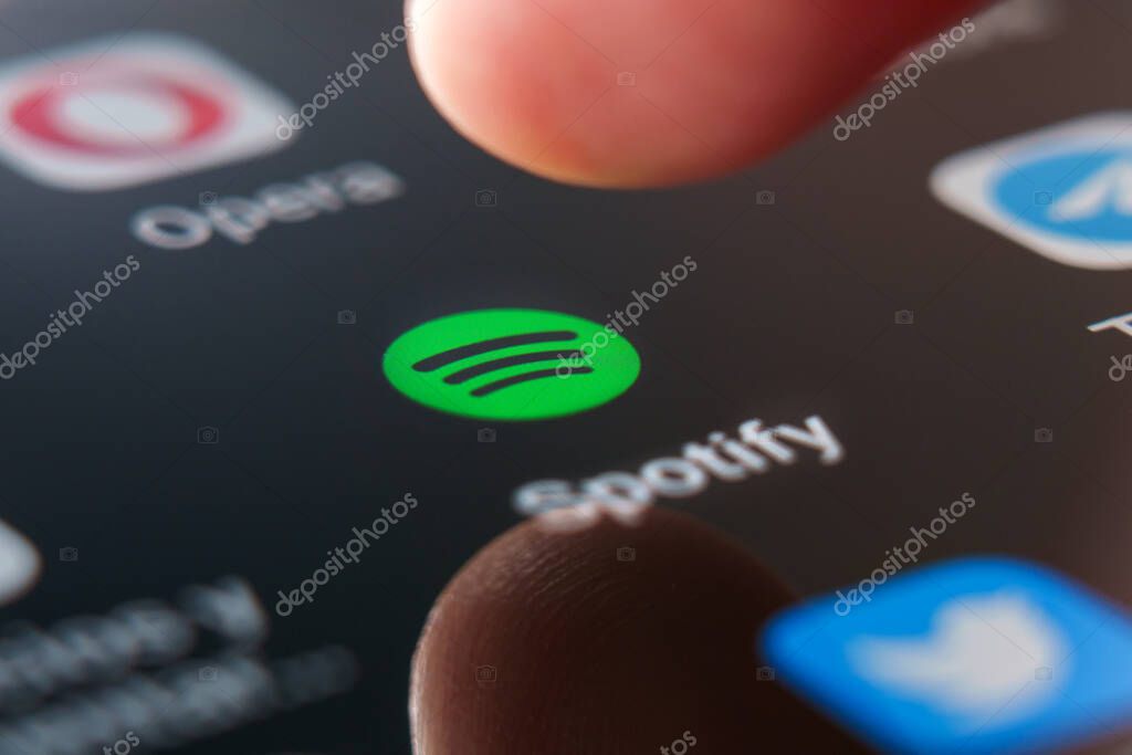 Oviedo, Spain - July, 04, 2023: Spotify logo app on mobile screen close up with touching finger. Global music streaming service