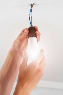 Parlayan bir elektrik enerjisini değiştirip beyaz ampulü yakın plan çekiyoruz. Kavramsal görünüm