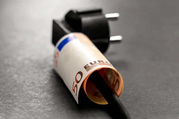 stock image Euro banknote on a electrical household appliance cord with black plug. Conceptual view. Financial costs of electricity supply idea