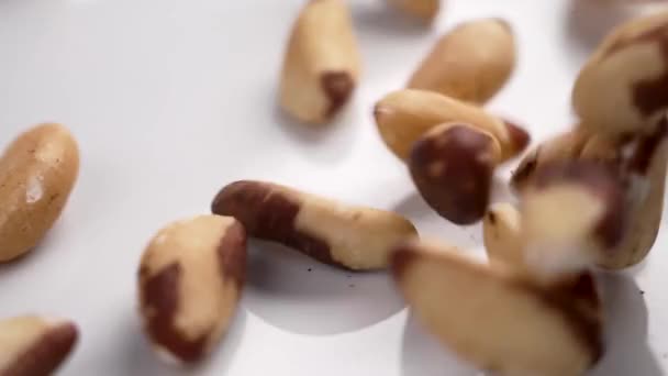 生巴西坚果掉在白色陶瓷盘上慢动作关闭 饮食健康小吃 — 图库视频影像