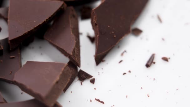 白いセラミックの背景に壊れたチョコレートのピースをダーククラック マクロ ローテーション — ストック動画