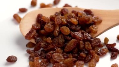 Tahta kaşıkta koyu kahverengi üzümlü meyveler yakın mesafeden düşüyor. Kurumuş olgun üzümler.