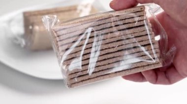 Paketlenmiş glütensiz diyet karabuğday gevreği. Elinde plastik sağlıklı kraker paketi var. Kapat.