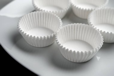 Doldurulmamış kağıtlı kek kalıpları beyaz bir kekin üzerine kapanıyor.