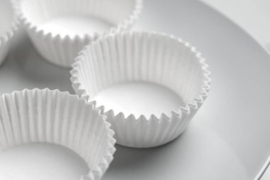 Kek ve muffinler kıvrımlı kağıt kalıplar. Beyaz zemin üzerinde tatlı hamur işleri için boş istiflenmiş mutfak araçları