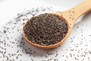 Tahta kaşık dolusu sağlıklı chia tohumu. Beyaz seramik yüzeydeki Omega 3 yağ asitlerinin kaynağı