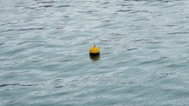 Mavi sudaki deniz dalgalarında yüzen sarı deniz şamandırası