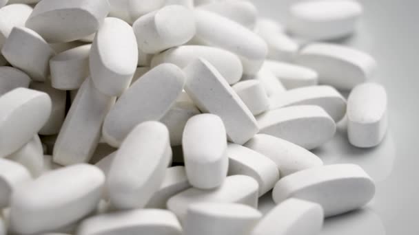 Elongated Medical Pills Spilled White Ceramic Background Rotation — Stock Video