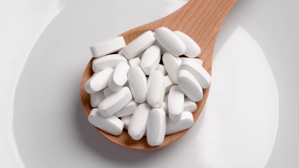 Белые Медицинские Таблетки Деревянной Ложке Керамическом Фоне Вращение Концепция Здравоохранения — стоковое видео