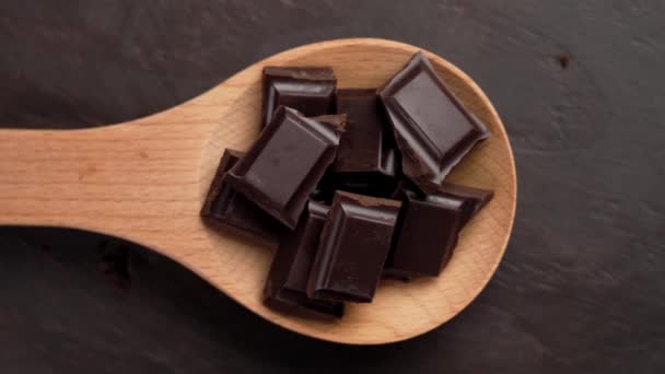 Sötét Keserű Csokoládé Darabjai Egy Fakanálban Barna Háttéren Közelről Forgás — Stock videók