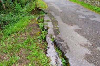 Deprem yüzünden ormanda çökmüş asfalt yol. Yaklaş.