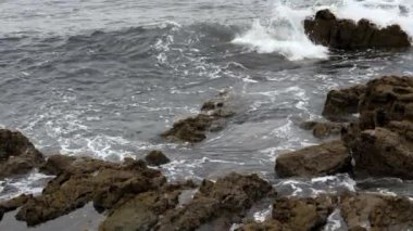 Soğuk sonbahar Biscay Körfezi dalgası kasvetli bir günde sert kayalara çarpıyor.