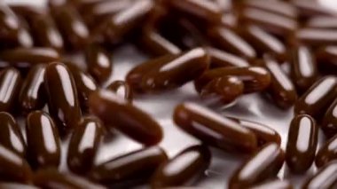 Yumuşak jel kapsülleri ve ayçiçeği lecithin yavaş çekimde düşüyor. Beslenme takviyeleri. Döndürme. Kapat.