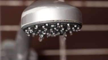 Banyoda eski bir duş başlığını açmak ve döşeme duvarında içme suyu akıtmak.