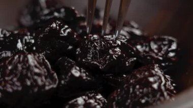 Siyah kuru erikler ya da çelik bir çatalda kurutulmuş kuru erikler.