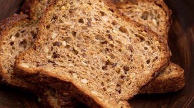 Tahta kırsal kahverengi tabakta koyu undan yapılmış tahıl ekmeği dilimleri. Döndürme. Üst görünüm