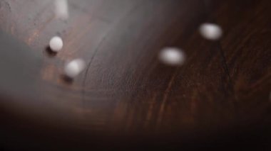 Tahta bir kaseye düşen homeopatik iyileştirici küreler. Bitki özlü doğal granüller. Alternatif tıp. Yavaş çekim