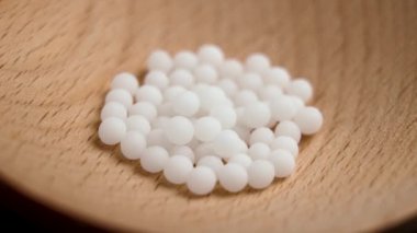 Tahta kaşıkta beyaz kürede homeopatik ilaç. Bitki özlü doğal granüller. Alternatif tıp. Döndürme