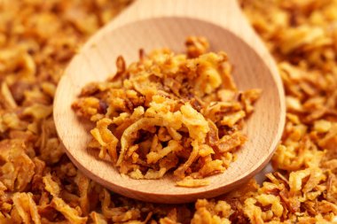 Tahta kaşıkta kızarmış soğan. Kavrulmuş altın arpacık soğanı. 