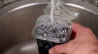 Böğürtlenleri plastik ambalajla yıkamak mutfakta akan suyla yavaş çekimde lavaboyu kapatmak.