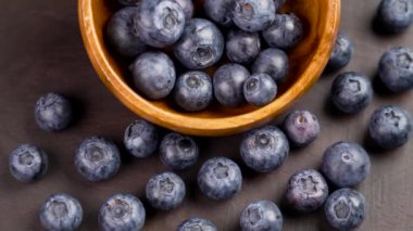 Tahta bir kaseye serpilmiş taze yaban mersini. Sulu dut meyveleri kapanıyor. Döndürme